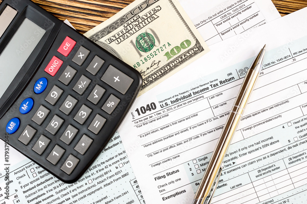 Calculator with one hundred dollar bill on the tax form. Top view. Calculator with one hundred dollar bill on the tax form. Top view.