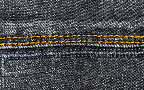 Blue and golden stitches on gray jeans. Close up.