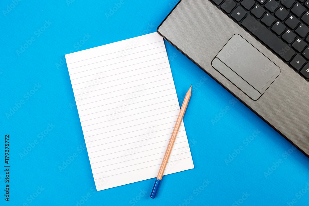 Open notepad with pencil and laptop on a blue. Top view. Business and education concept. Open notepad with pencil and laptop on a blue. Top view. Business and education concept.