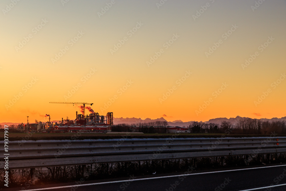 sun goes down behind an industry