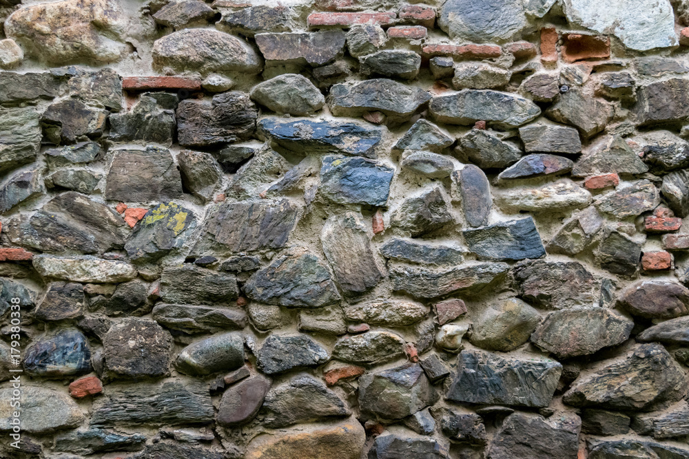 Medieval wall built of stone and bricks, background texture