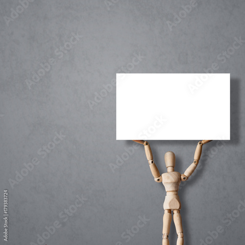 Wooden Mannequin on gray background holds up empty billboard or blank banner. Concept for advertisement or revolution protest photo