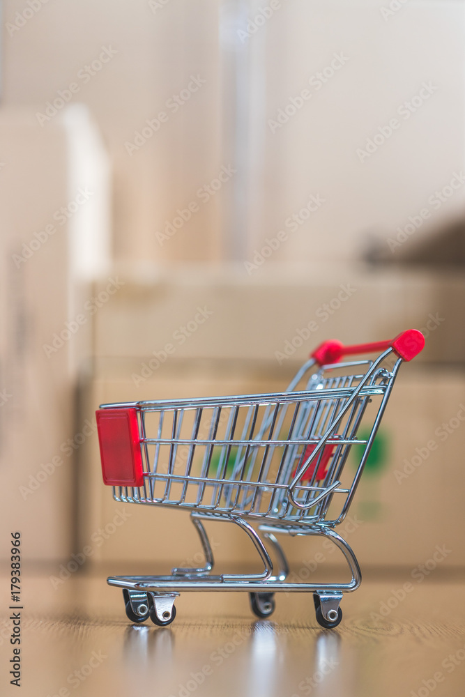 Mini Einkaufswagen mit Paketen im Hintergrund, Onlineshopping Mini Einkaufswagen mit Paketen im Hintergrund, Onlineshopping