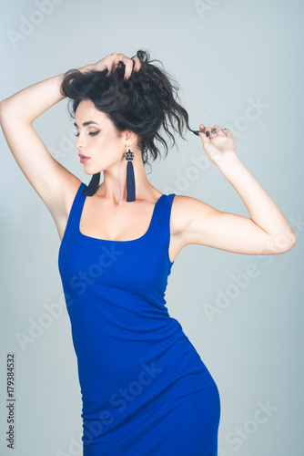 Girl with makeup face in blue dress on grey background