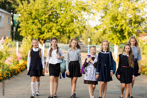 A group of schoolgirls with backpacks go to school