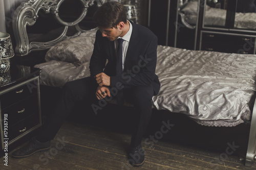a young man in a classic suit, one sitting on the bed.