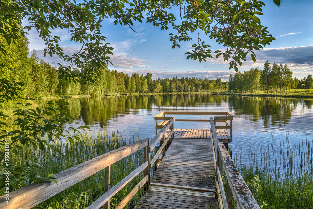 Obraz premium Molo z drewnianymi ławkami przy jeziorem w Lapland