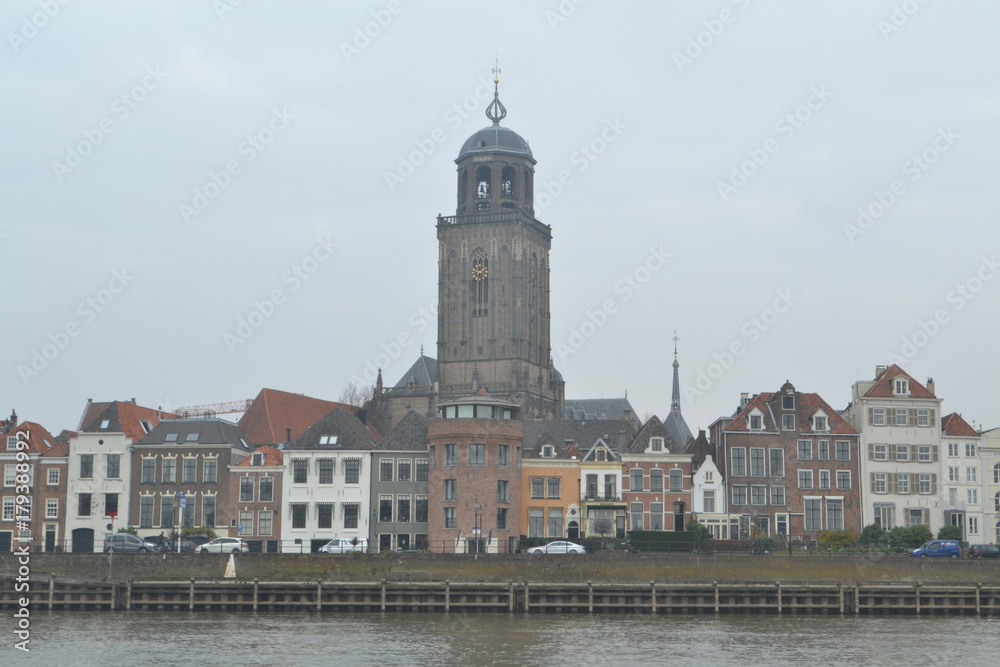zicht op Deventer vanaf de IJssel op oude huizen en Lebuniuskerk op grijze dag