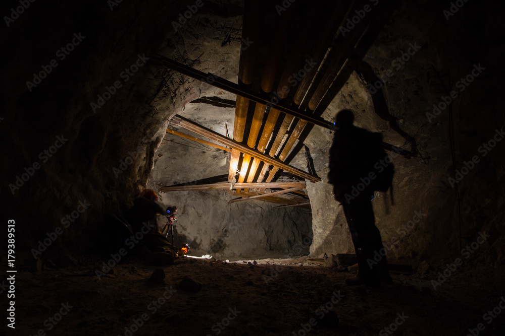 Fototapeta premium Underground mine shaft iron ore tunnel gallery with miner and pipes