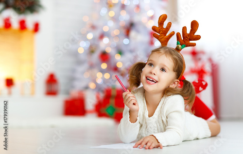 child girl writing letter santa home near Christmas tree