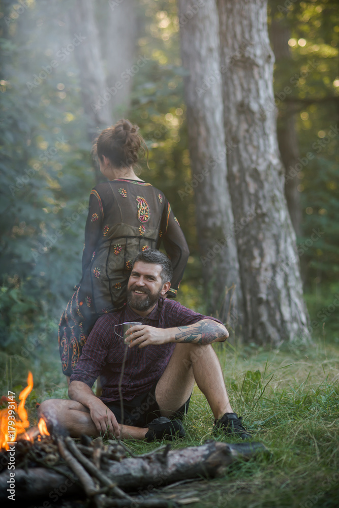Couple of hikers relax at campfire in forest Couple of hikers relax at campfire in forest