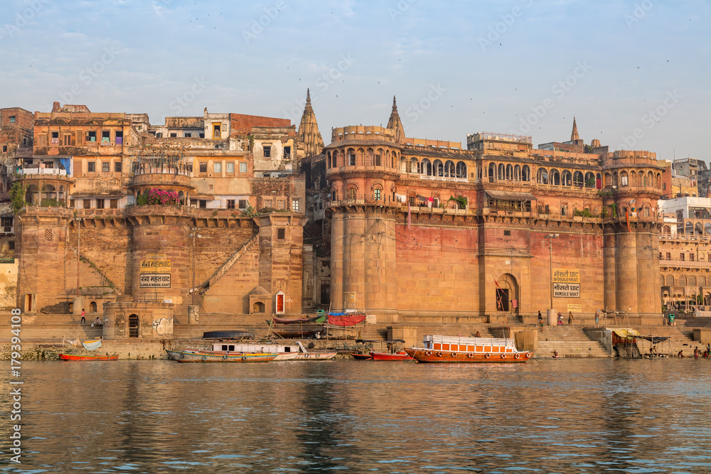 Historic Varanasi city with old architectural buildings and ancient temples along the Ganges river ghat as viewed from a boat.