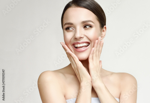 Happy beautiful girl holding her cheeks with a laugh   looking to the side. Expressive facial expressions  .Cosmetology and Spa
 
 photo