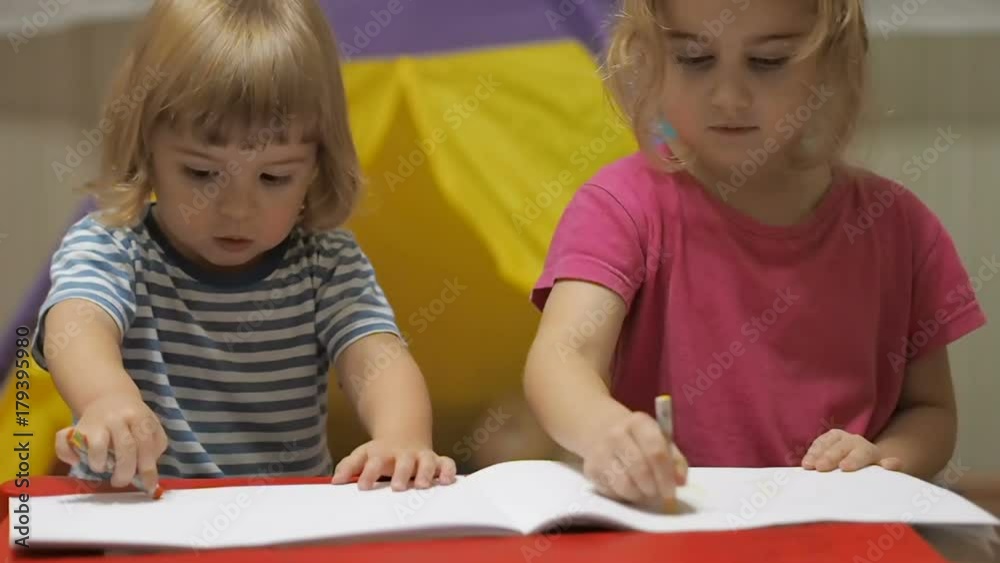 Two little children girl and boy sitting at table drawing. Brother and sister drawing with colorful crayons Two little children girl and boy sitting at table drawing. Brother and sister drawing with colorful crayons