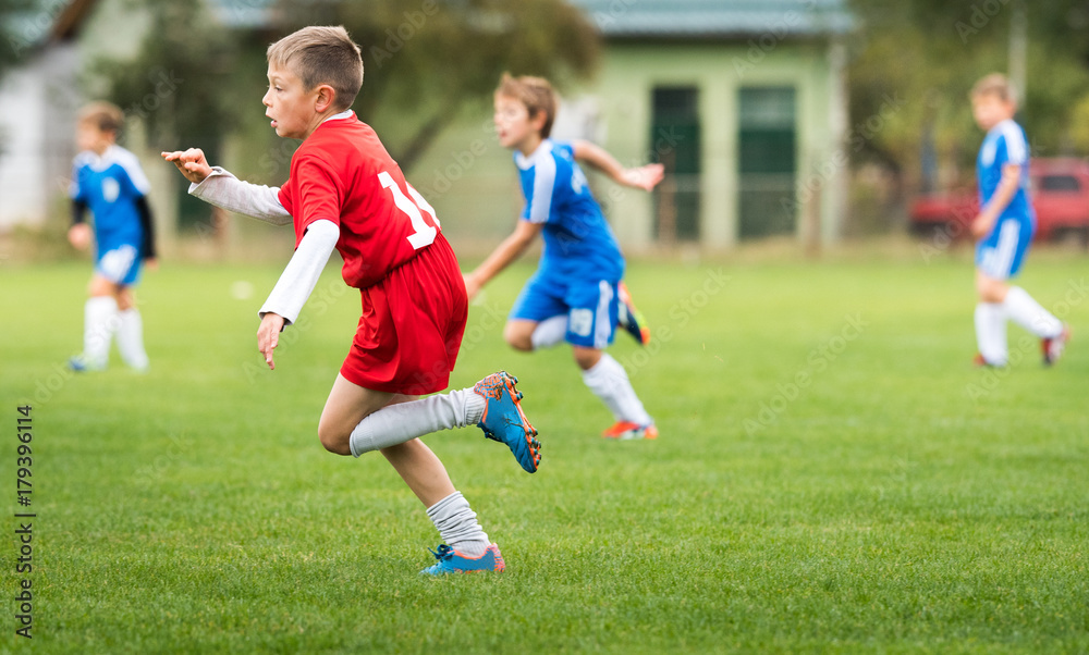 Boy kicking football on the sports field Boy kicking football on the sports field