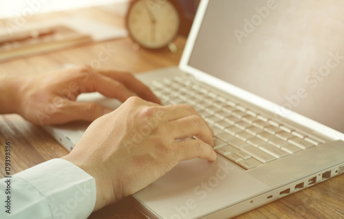 business man is working on his laptop with document and clock background