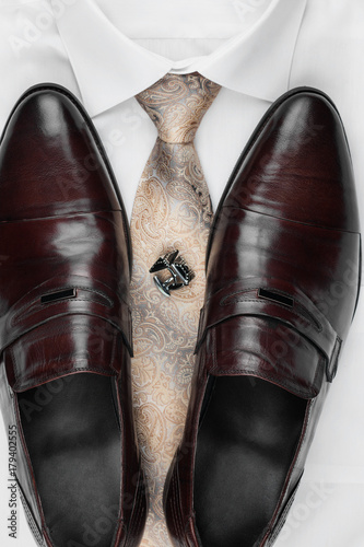 Pair of classic brown shoes standing on a shirt and tie. Men's fashion.