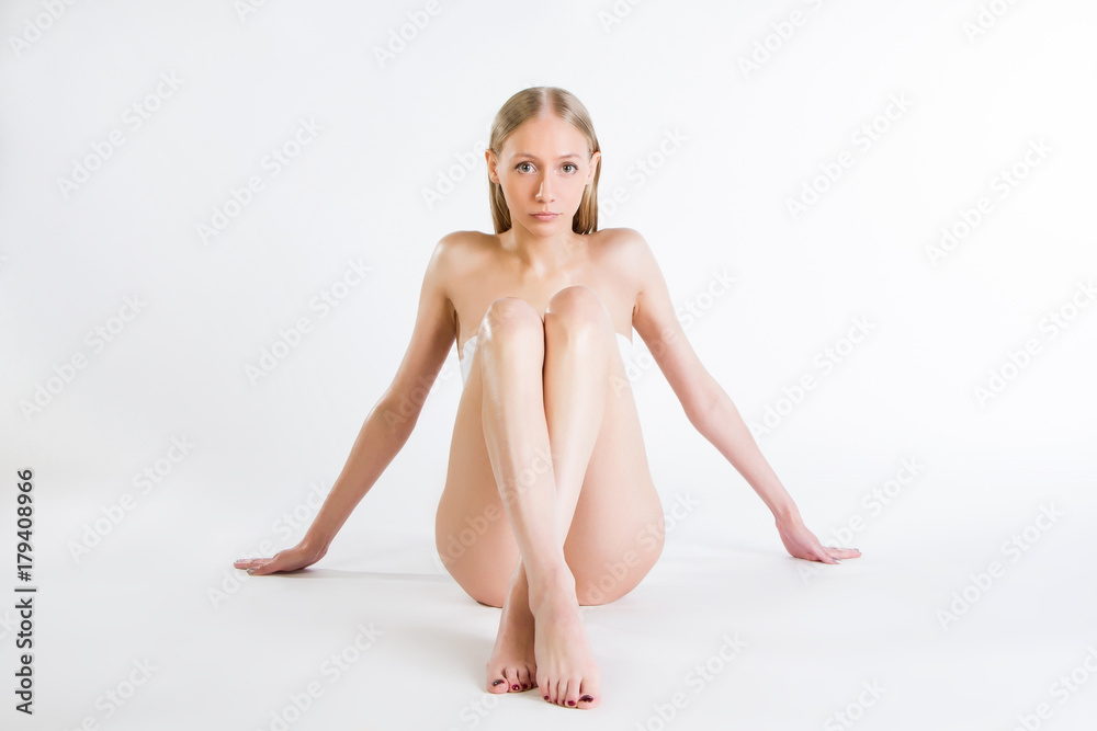 Obraz premium Beautiful slim girl is sitting on a white background