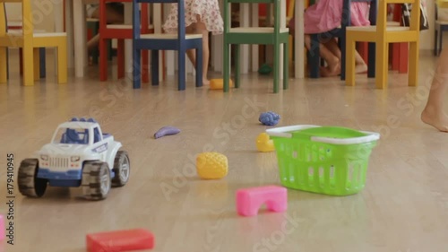 Children play at a kindergarten. Kids run at the playroom. Baby's legs and toys at playschool