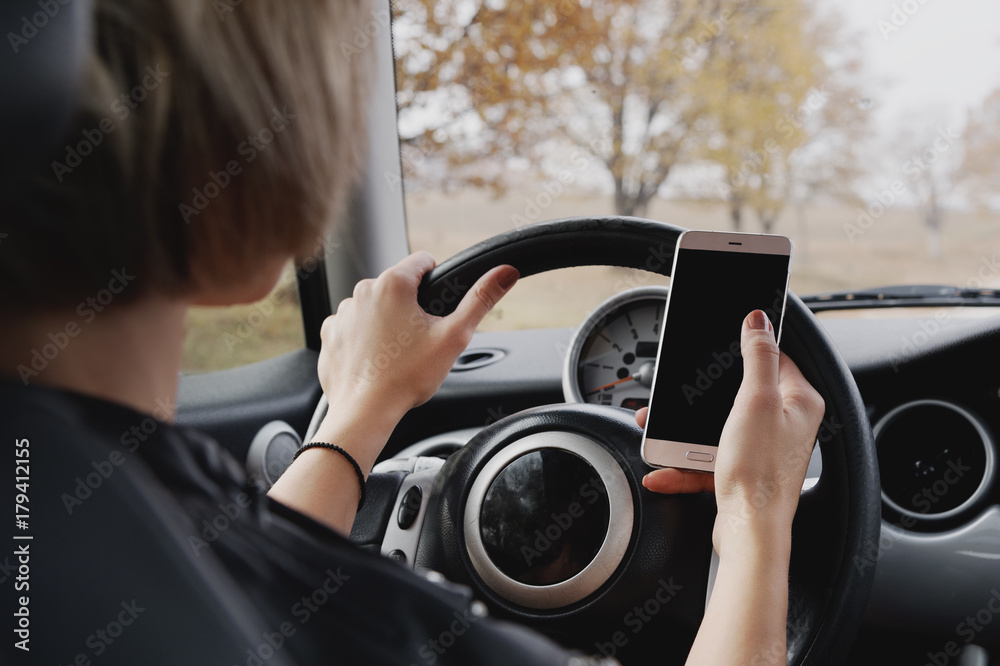 girl driving a car typing text on the phone and looking out the window girl driving a car typing text on the phone and looking out the window
