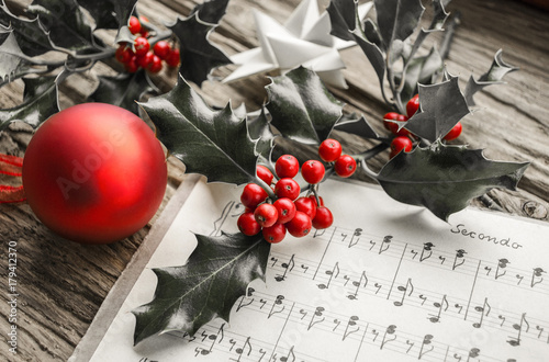 Alte handgeschriebene Musiknoten mit Ilex Zweig, roten Beeren und roter Weihnachtskugel, Weihnachten, xmas