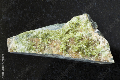 raw crystal of green Vesuvianite gemstone on dark photo