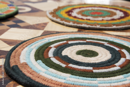 Brightly coloured woven placemats on a marquertry table top