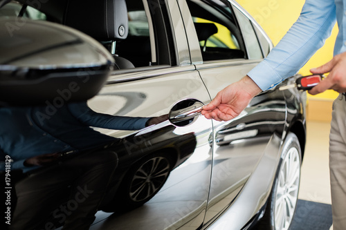 Close up of man opening a black car door without key, keyless opening system © Zdenka