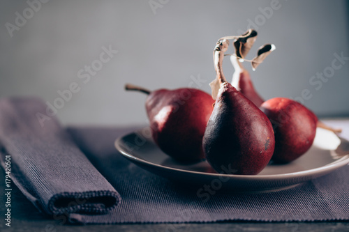 Plate with delicious red bartlett pears on dark background