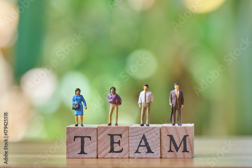 Miniature 4 people standing on wood word team as background business concept with copy space.