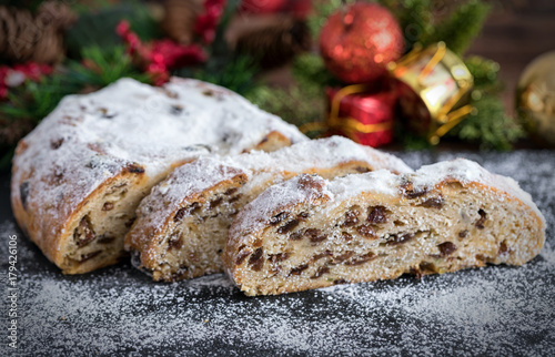 Weihnachtlicher Christstollen in Scheiben auf dunkelem Untergrund photo