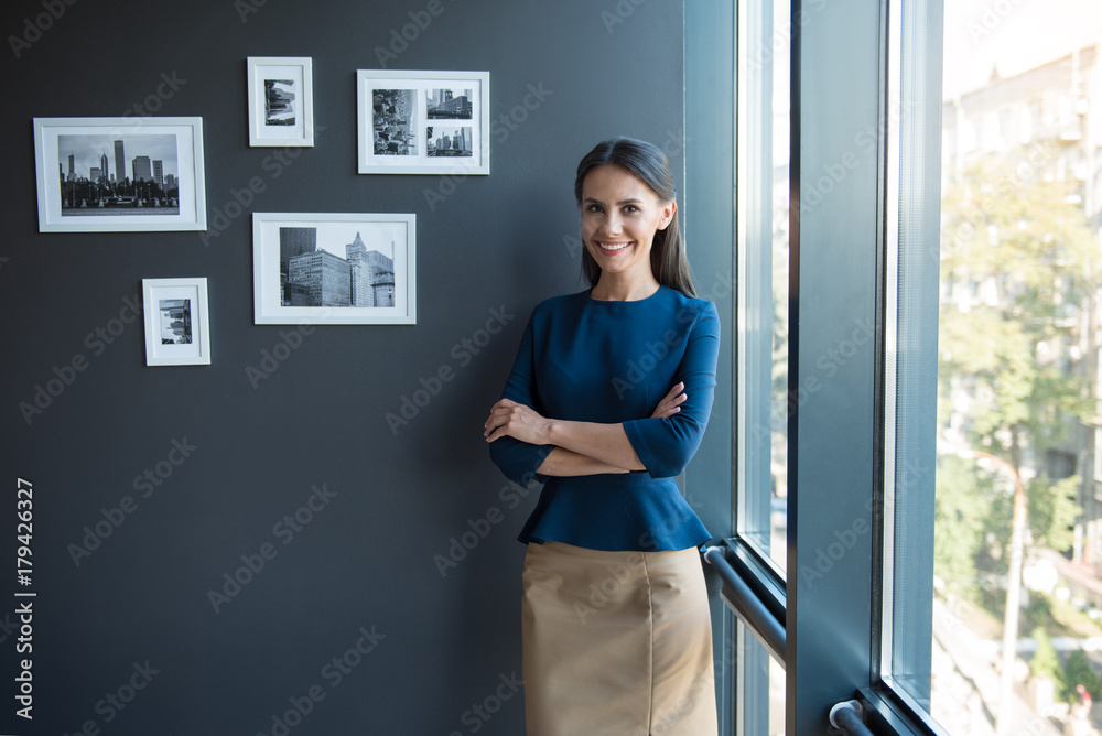 Joyful woman is posing near window