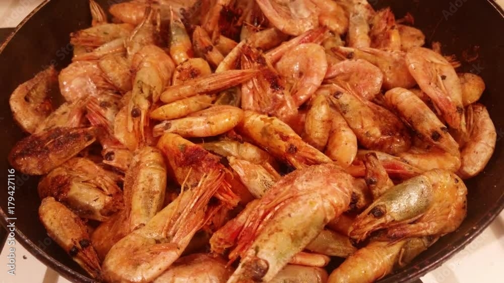 Delicious medium-sized shrimps with the heads fried on a pan with garlic and spices
