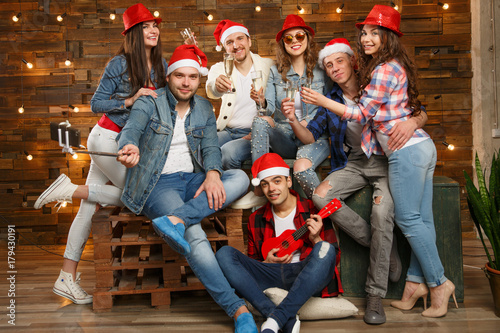 Party with group friends wearing Santa s hats. Young people  hipsters sharing good and positive mood  celebrate special occasion. Midnight at New Year s Eve party or christmas.
