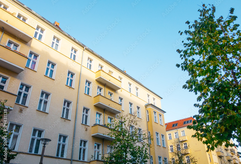 yellow apartment building with green tree in hdr look