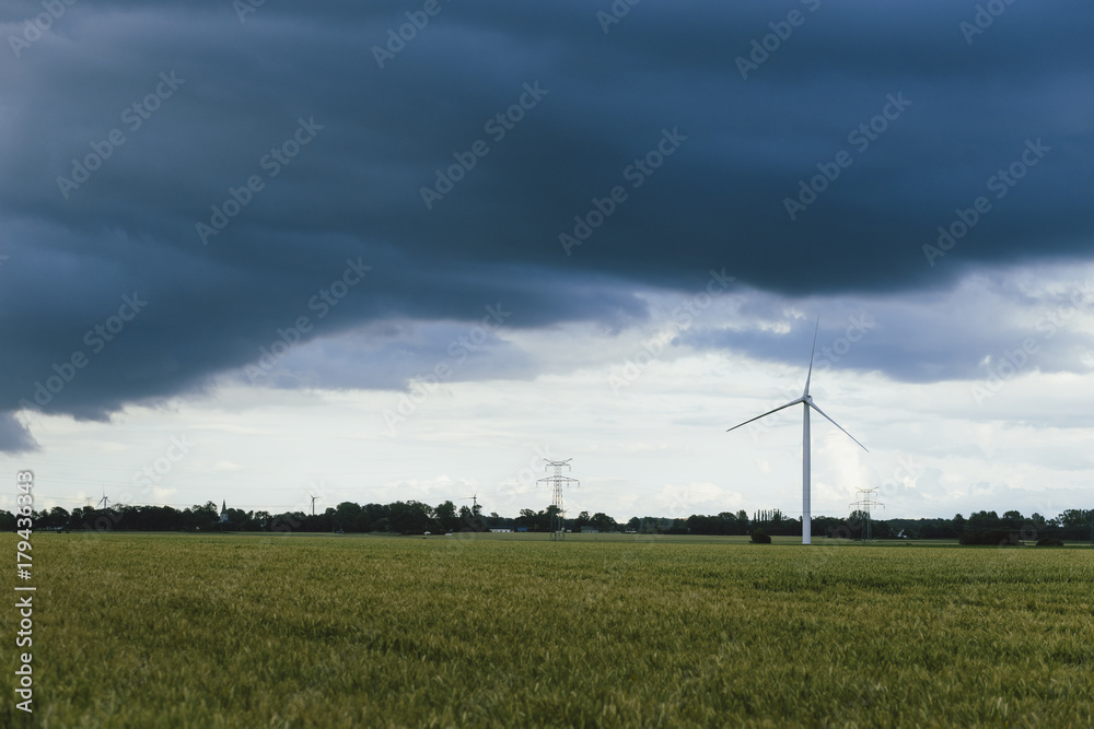Wind turbines for electrical power generation in green agricultural fields in Normandy, France. Renewable energy sources, industrial agriculture concept. Environment friendly energy production Wind turbines for electrical power generation in green agricultural fields in Normandy, France. Renewable energy sources, industrial agriculture concept. Environment friendly energy production
