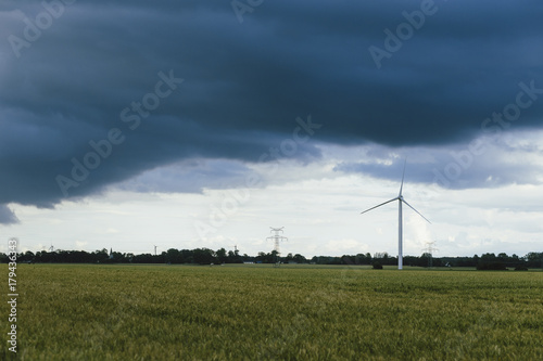 Wind turbines for electrical power generation in green agricultural fields in Normandy  France. Renewable energy sources  industrial agriculture concept. Environment friendly energy production