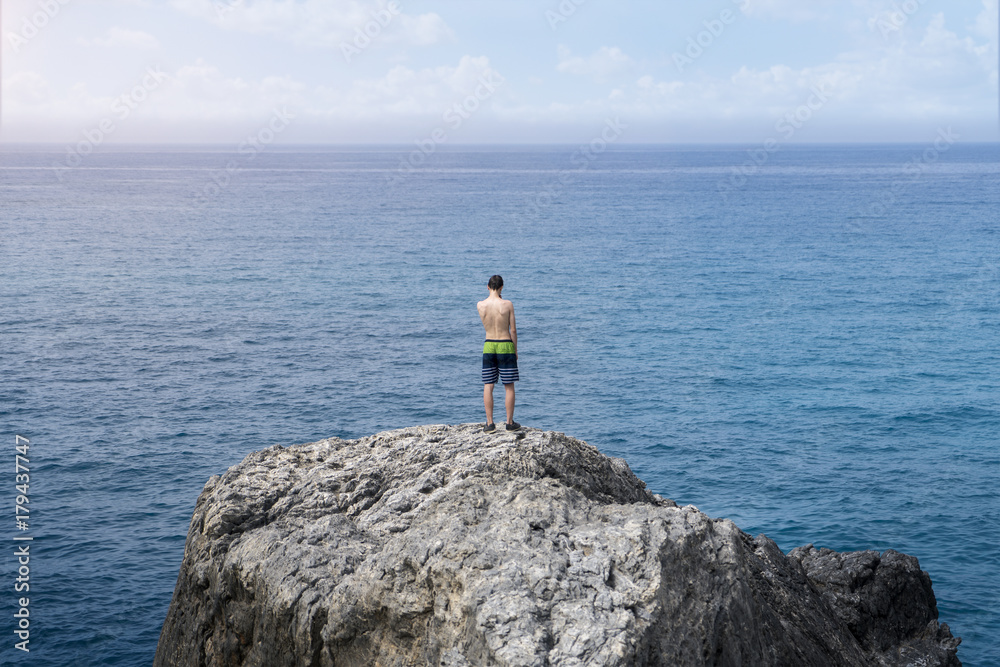 young man standing on a cliff