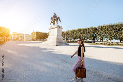 Young business lady walking with bag at the Peyrou park during the morning light in Montpellier city in France. Wide angle view with Louis statue