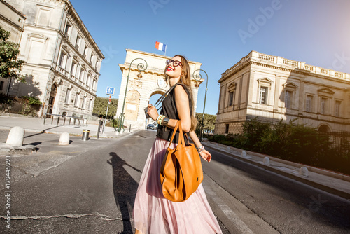 Lifestyle portrait of a businesswoman walking with bag on the street in front of the Triumphal Arch in Montpellier city, France