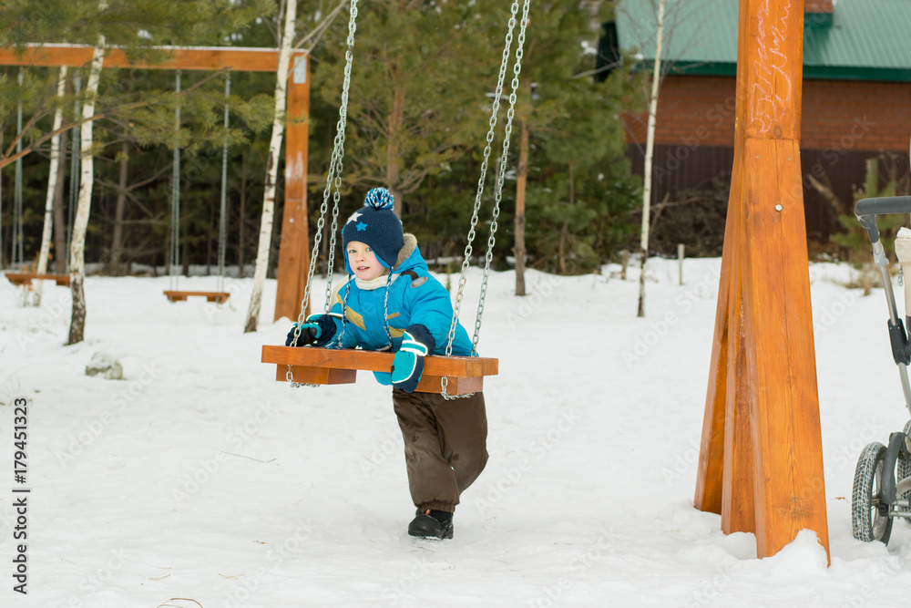 Happy child on swings at a winter park