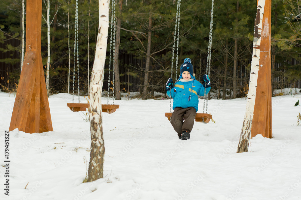 Happy child on swings at a winter park