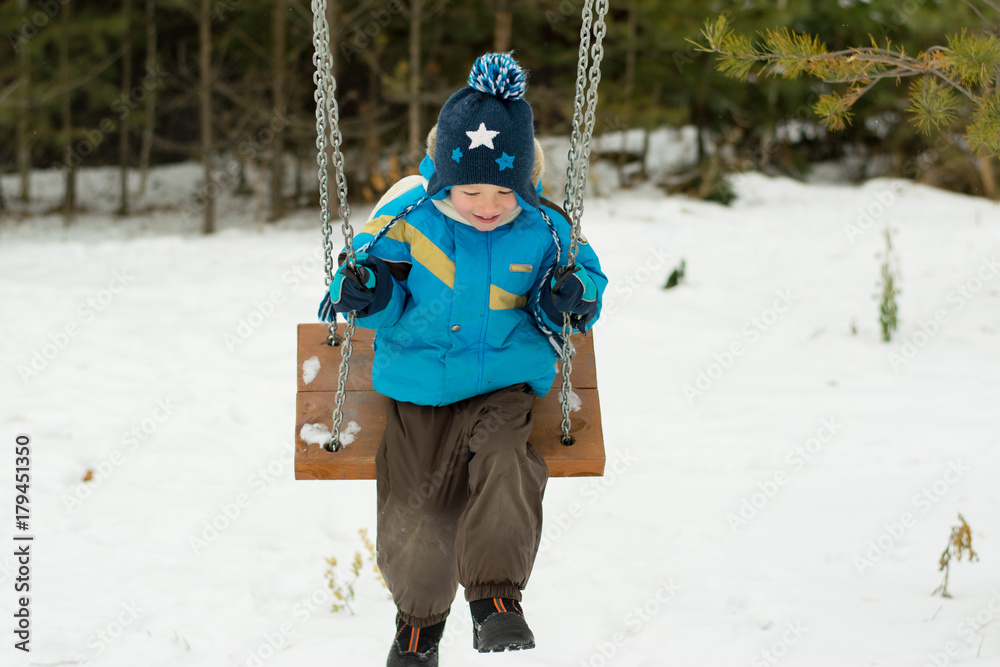 Happy child on swings at a winter park