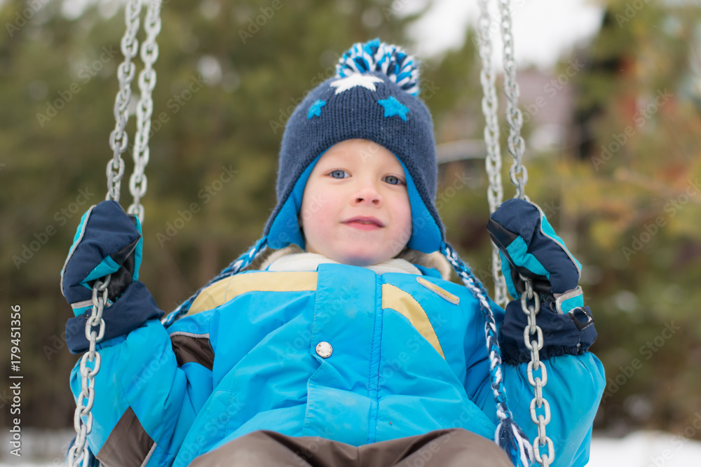 Happy child on swings at a winter park