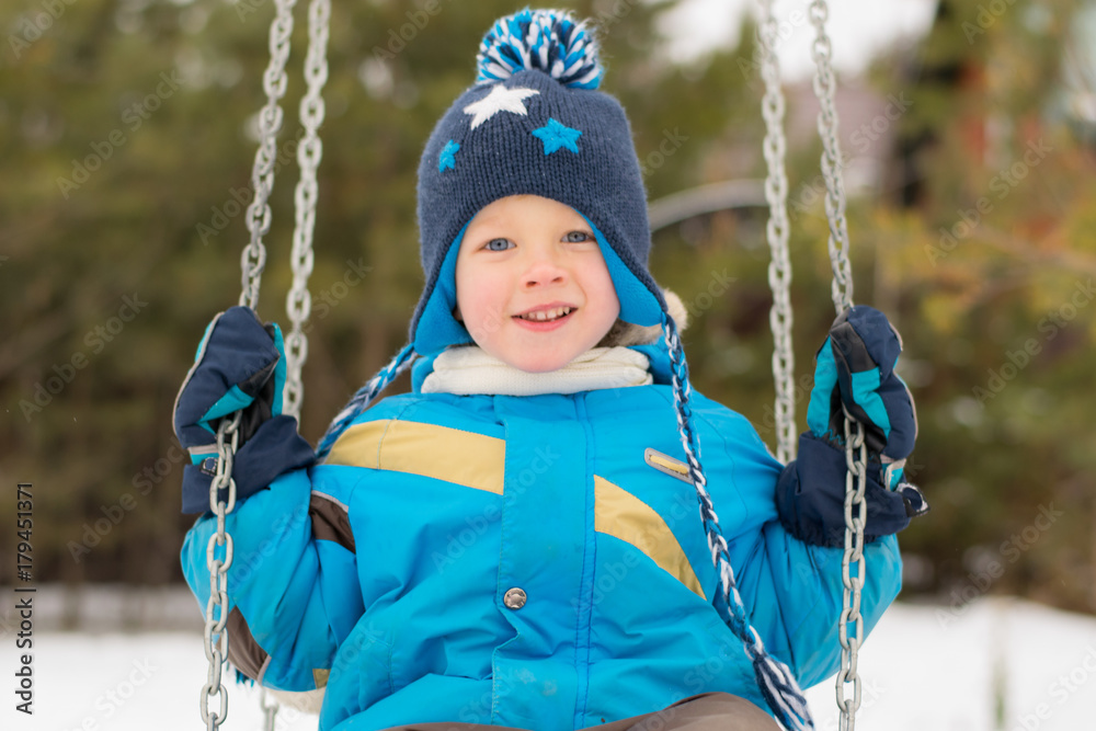 Happy child on swings at a winter park
