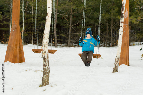 Happy child on swings at a winter park