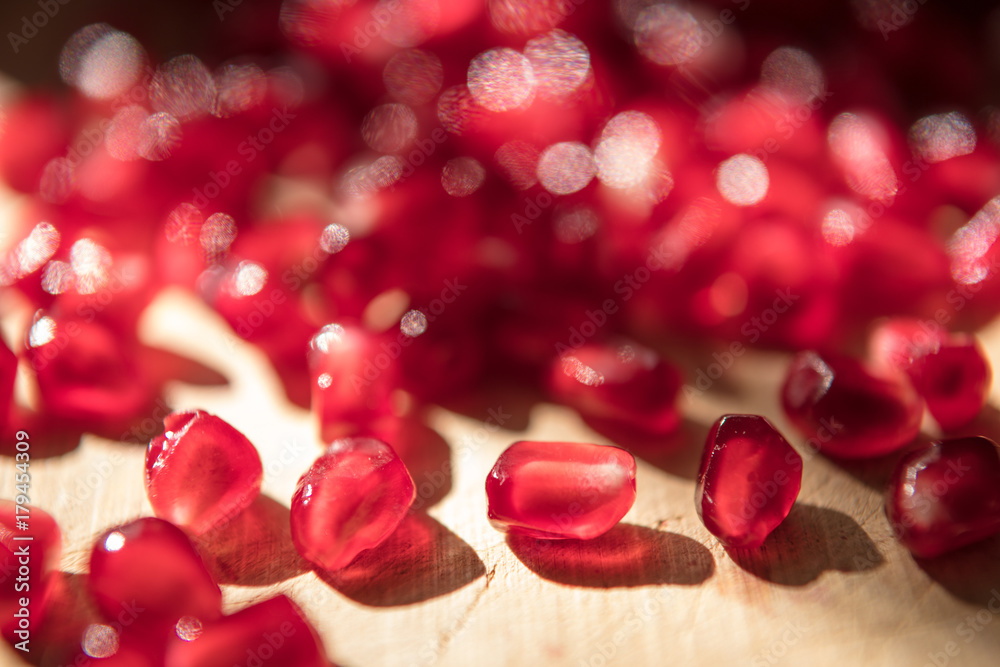 A pomegranate fruit broken open. Seeds are spilling on to wooden table A pomegranate fruit broken open. Seeds are spilling on to wooden table