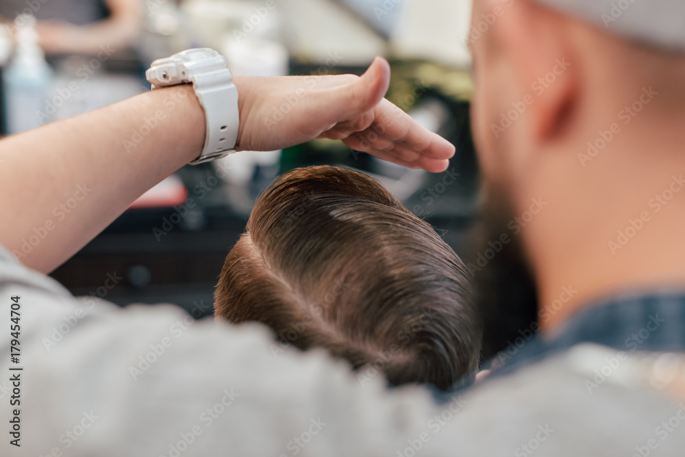 Fototapeta premium A man who shaves a beard with a dangerous razor in a barbercosh.