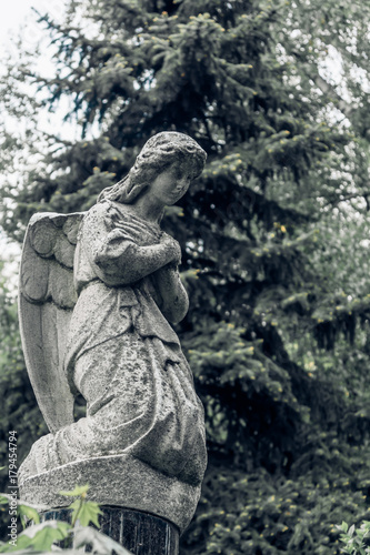 Stone Angel on his knees in the old cemetery - vintage toning © Stanislav Ostranitsa