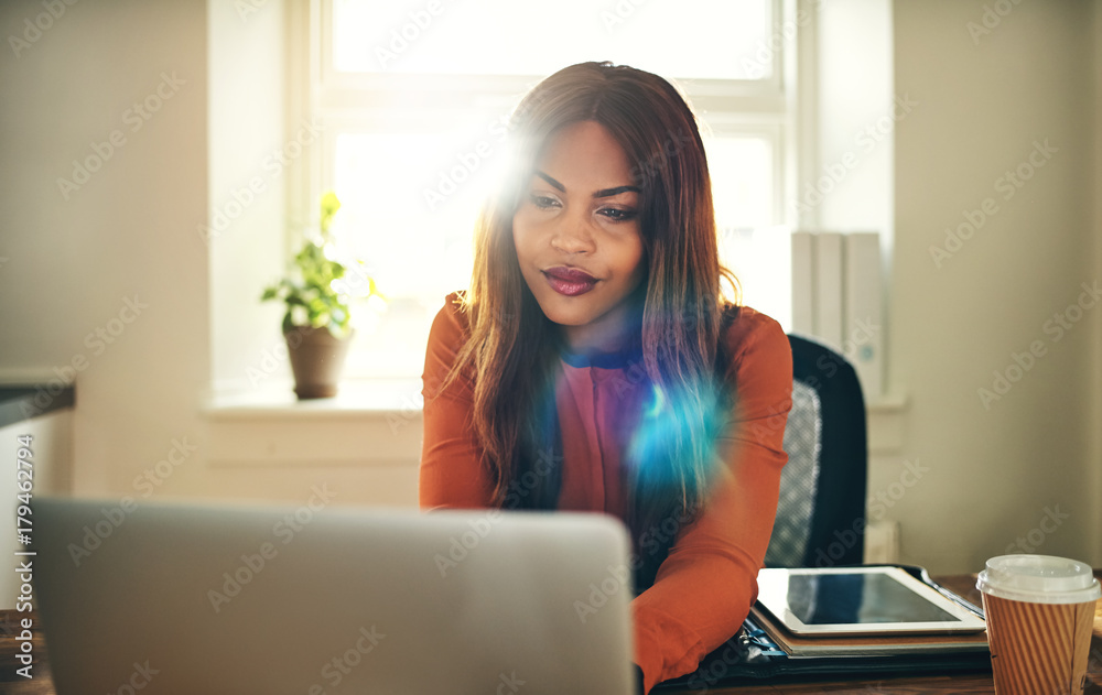 Focused young woman working online in her home office